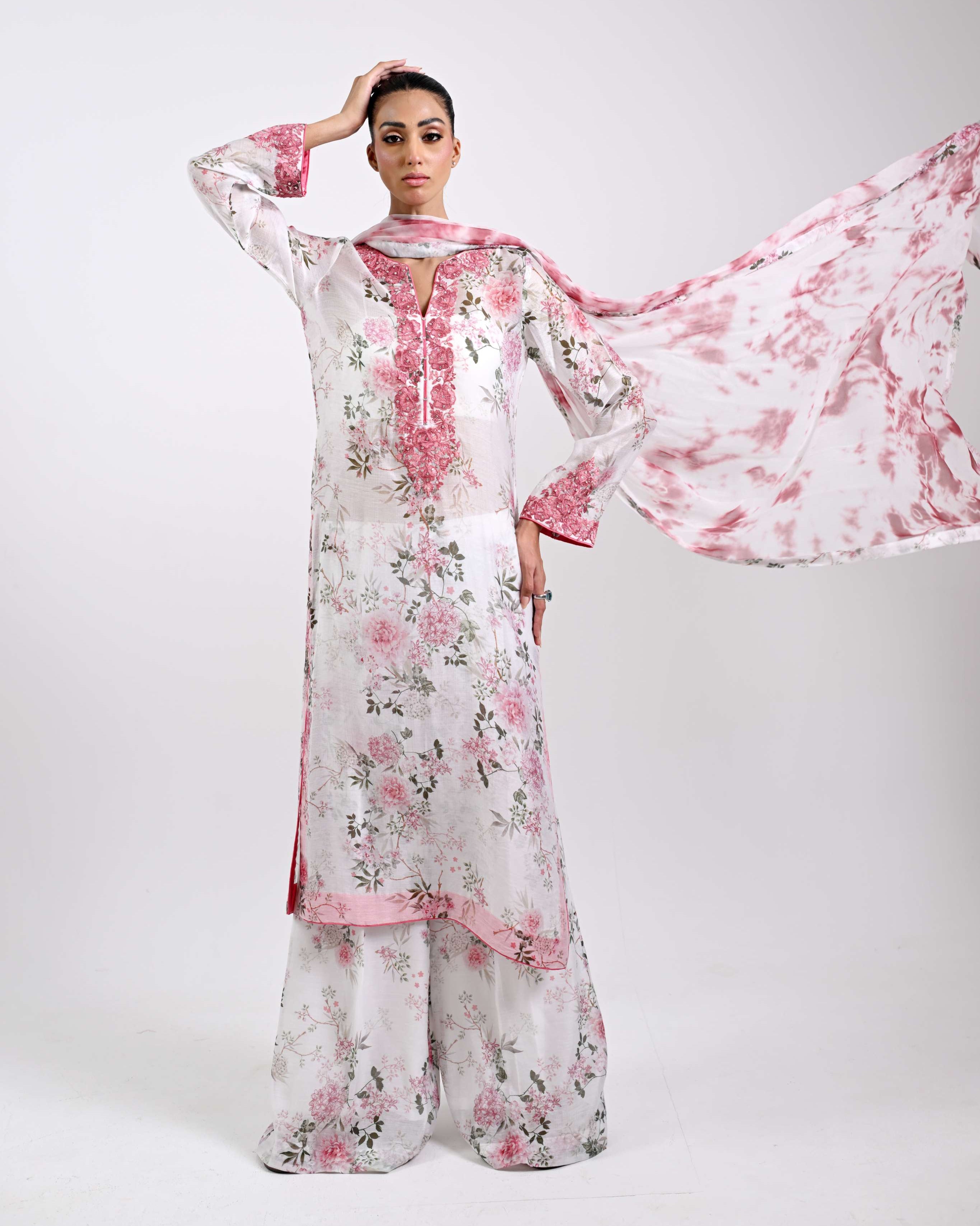 Woman wearing a floral dress with a pink scarf on a white background