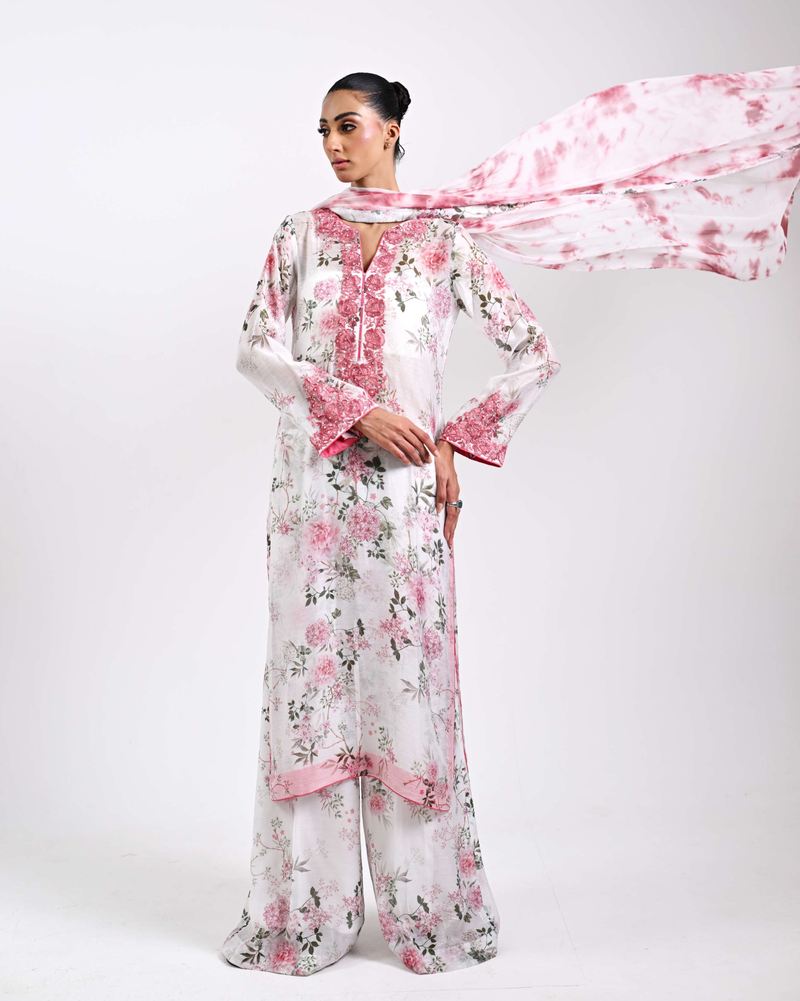 Woman wearing a floral outfit with a pink scarf on a white background