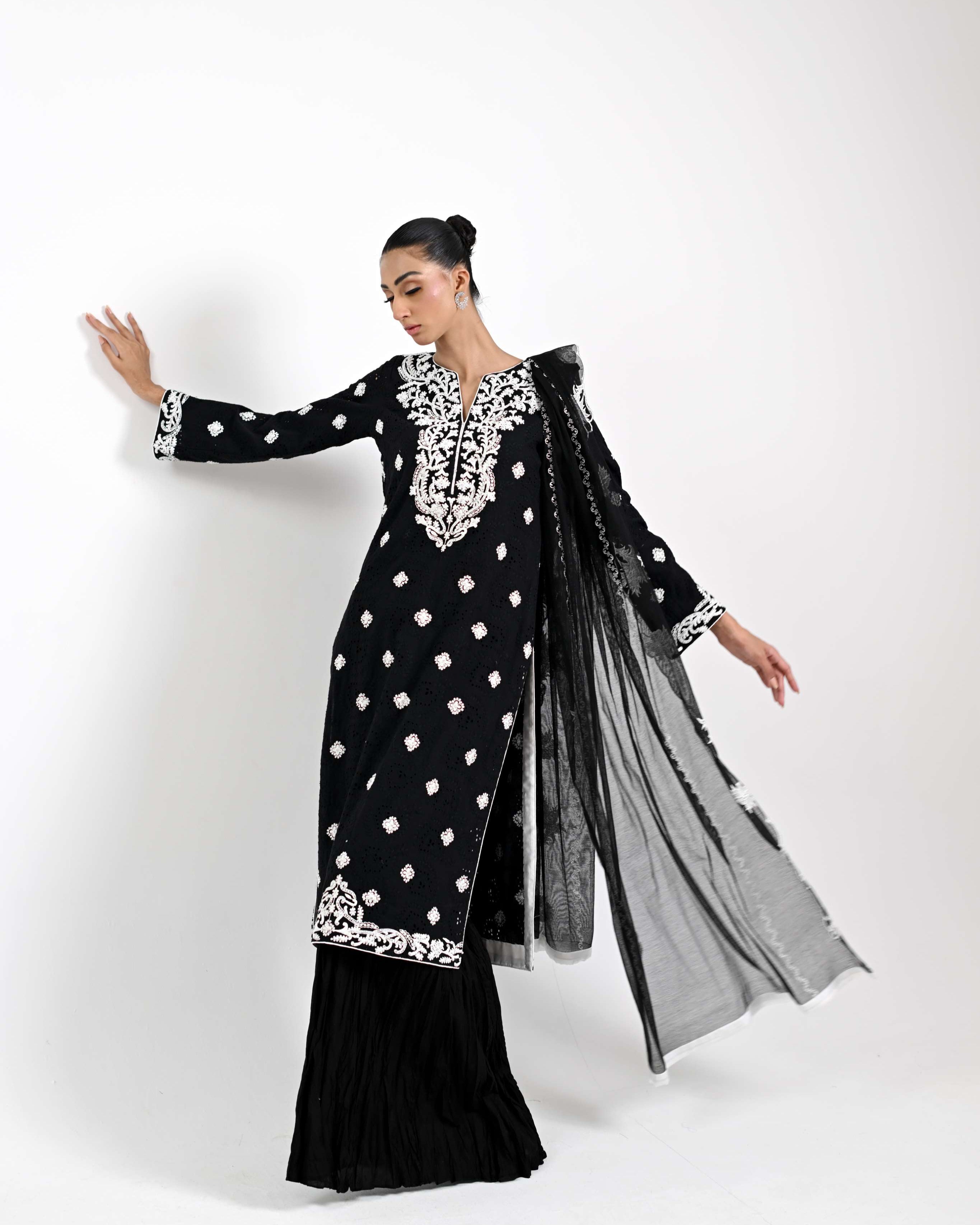 Woman wearing a black and white traditional outfit with silver embroidery on a white background