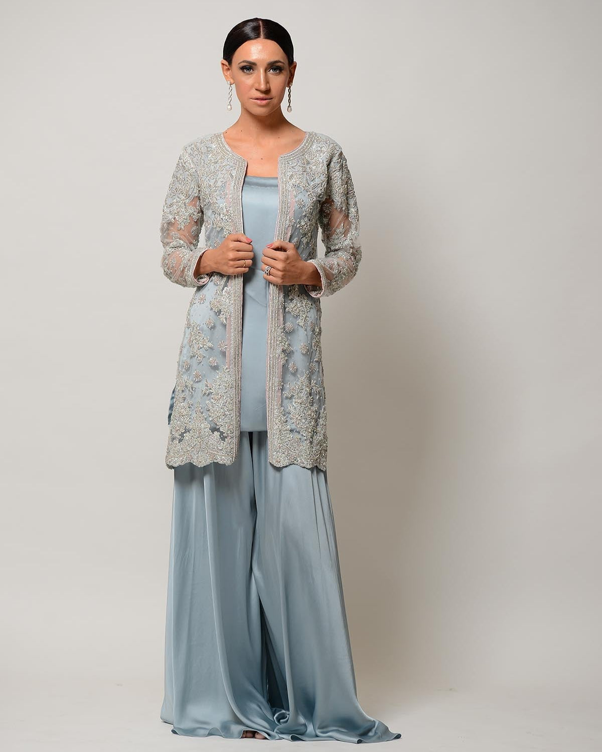 Woman wearing a light blue dress with a floral cardigan on a plain background