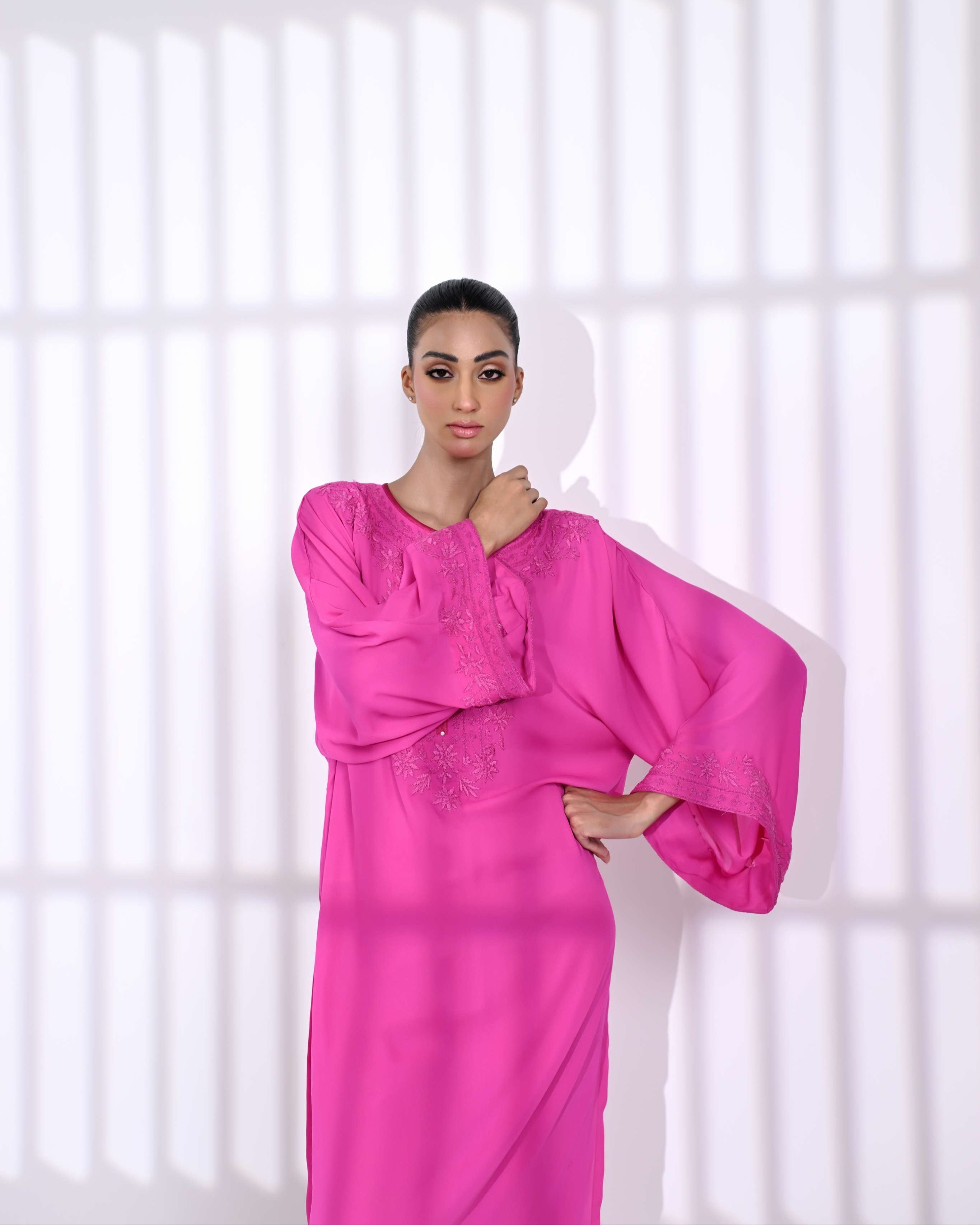 Woman wearing a bright pink dress against a white background