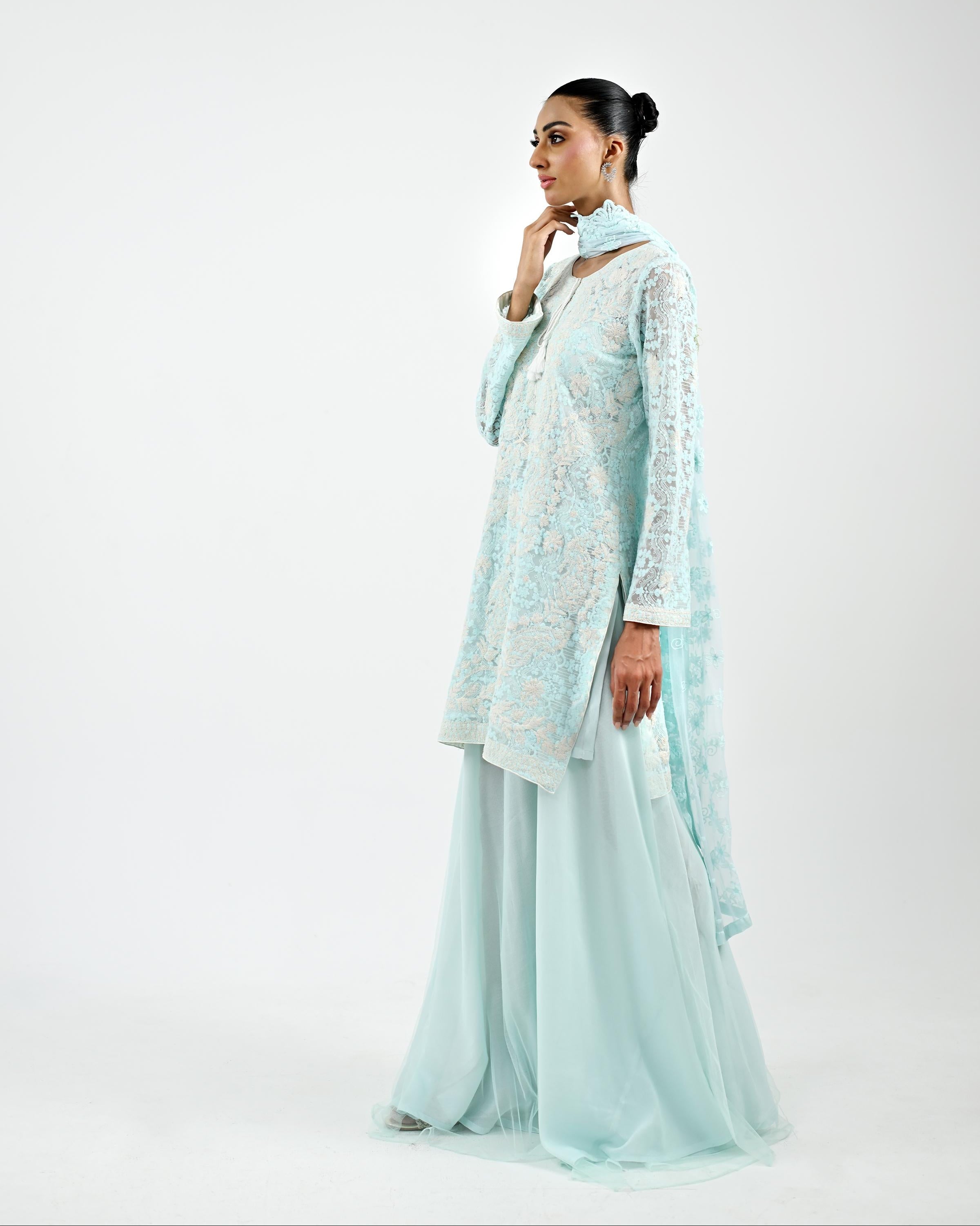 Woman wearing a light blue traditional outfit with a matching dupatta on a white background