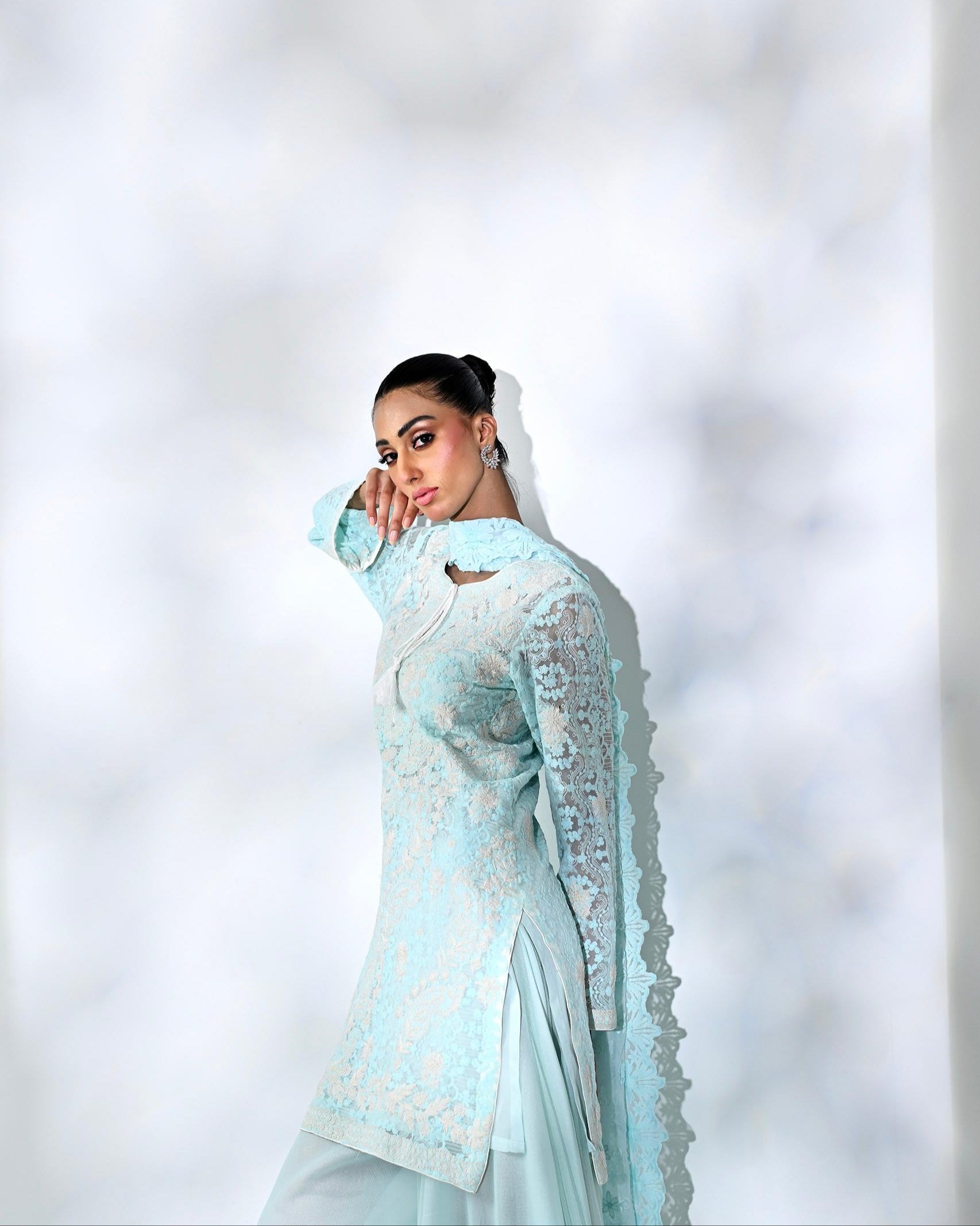 Woman in a light blue traditional outfit against a blurred white background