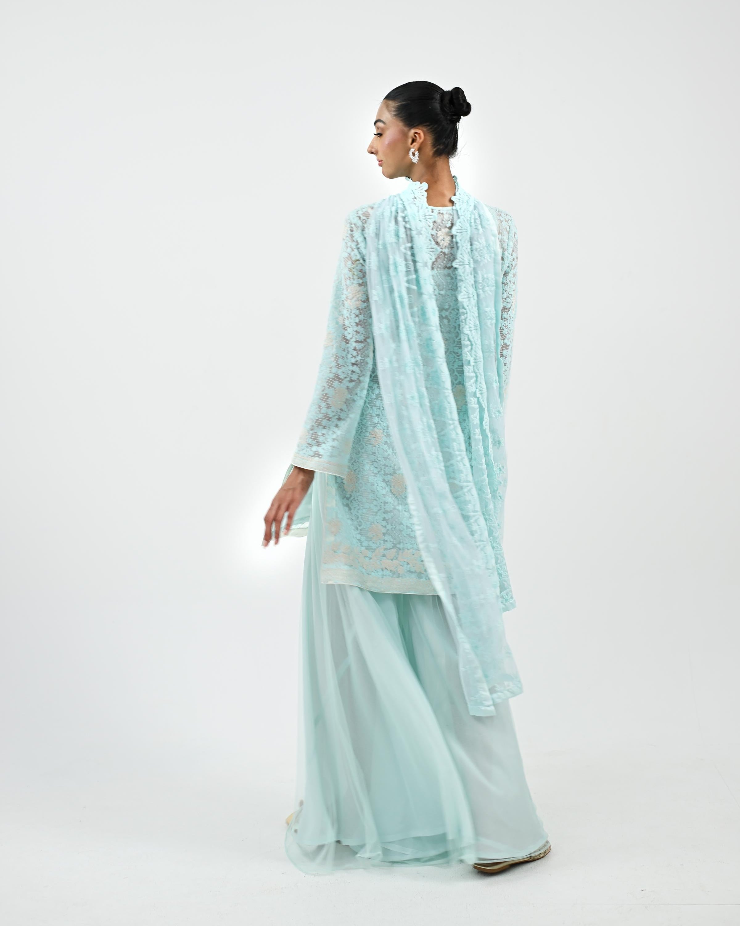 Woman wearing a light blue traditional outfit with a matching dupatta on a white background