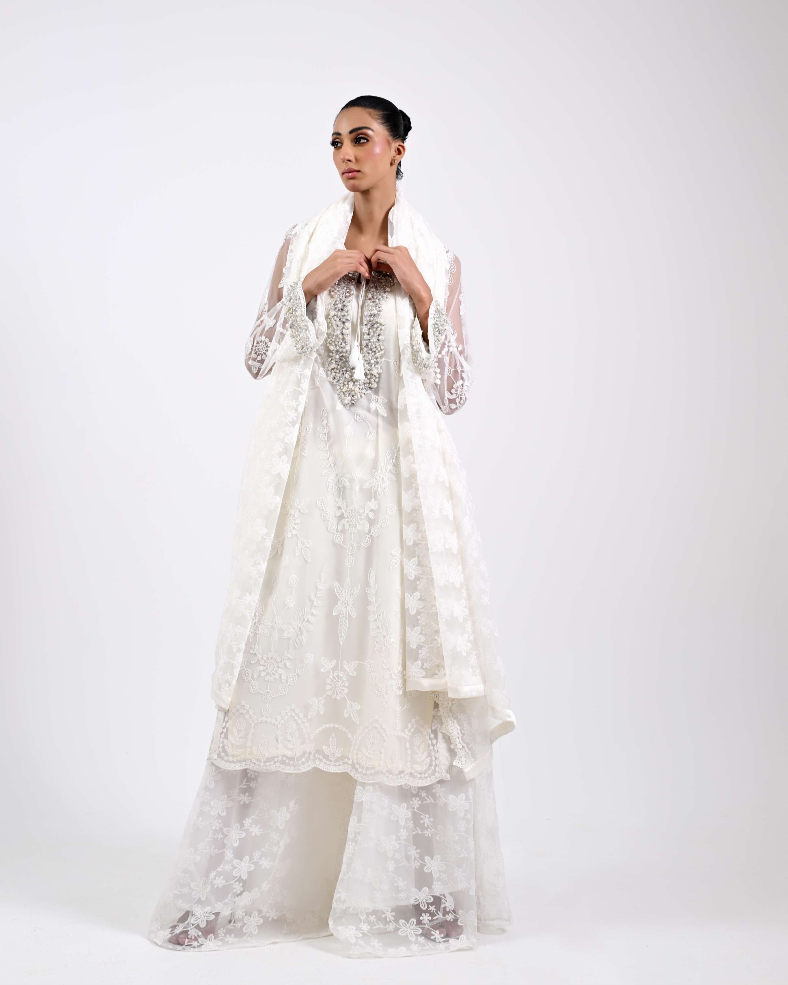 Woman wearing a white embroidered dress on a white background