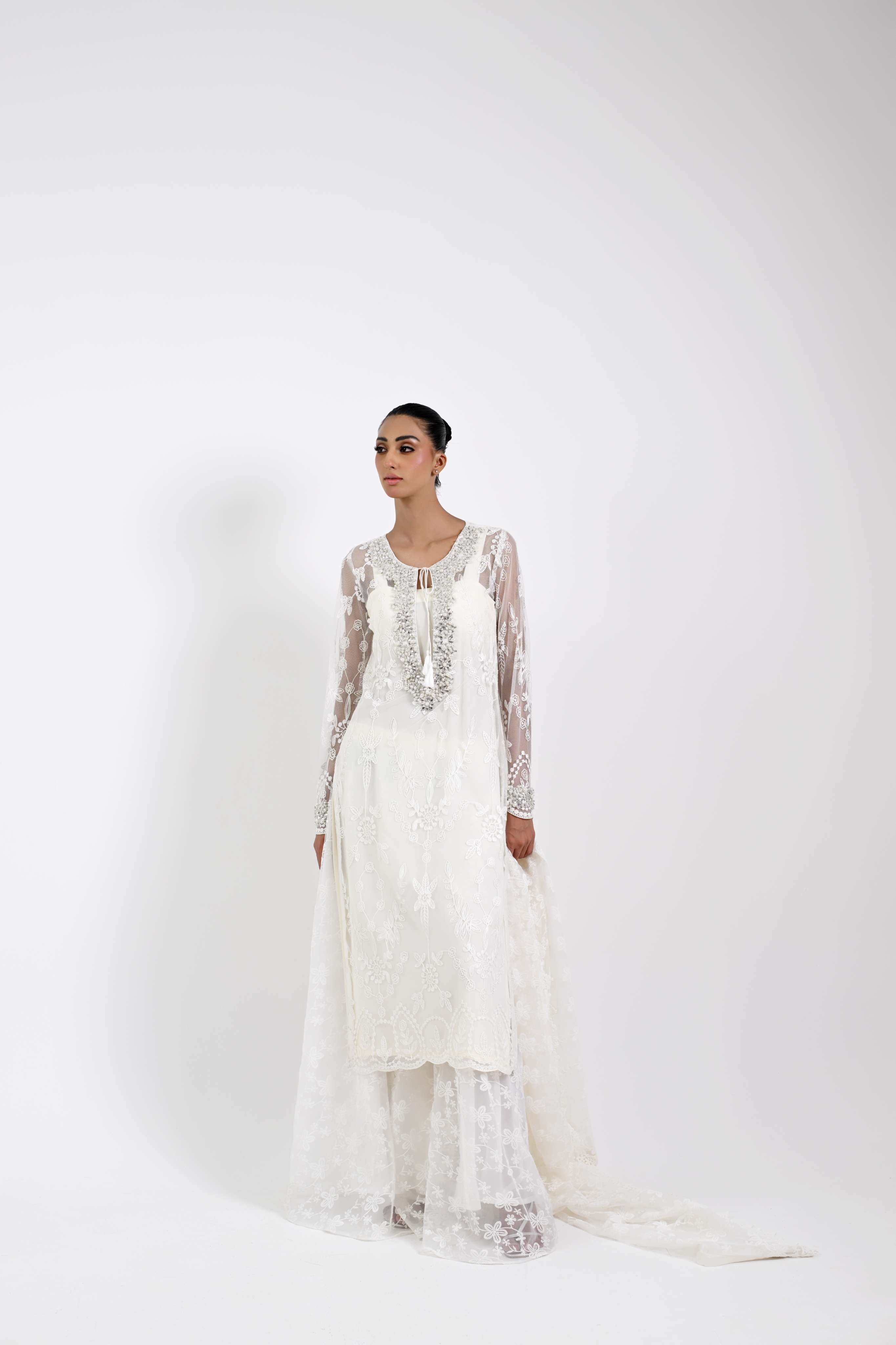 Woman wearing a white embroidered dress on a white background