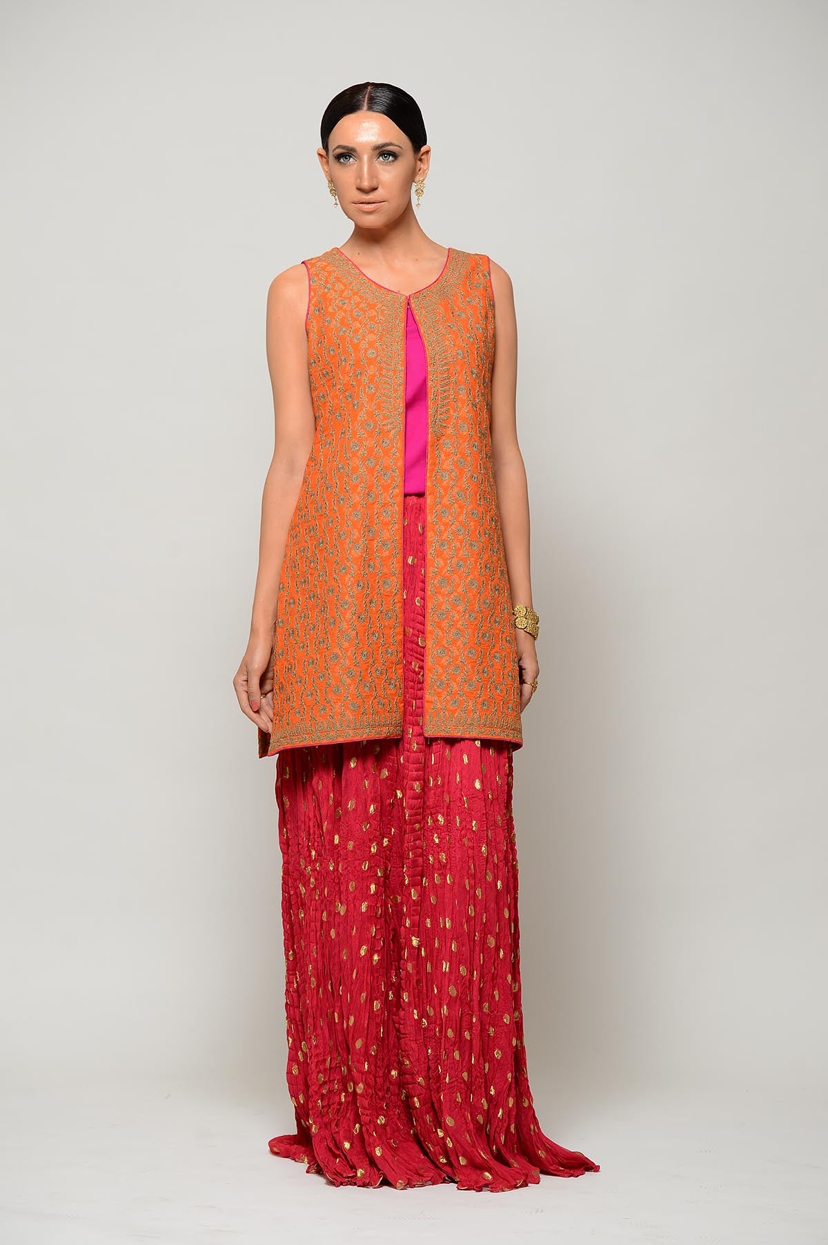 Woman wearing an orange and pink traditional outfit against a plain background