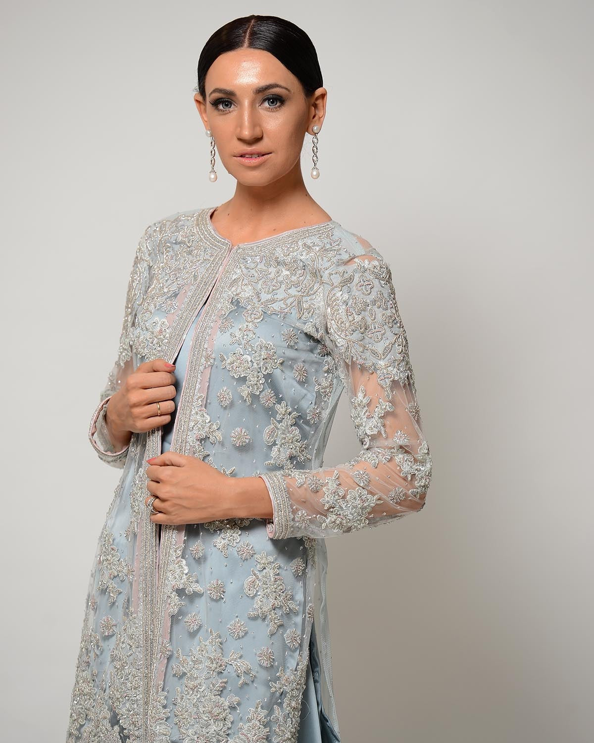 Woman wearing a light blue embroidered outfit with a matching dupatta on a plain background