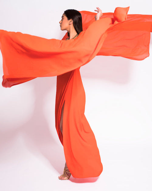 Woman in an orange dress with a long train against a white background