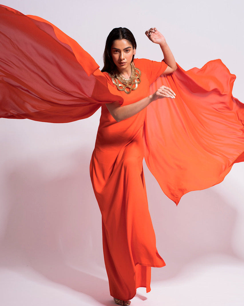 Woman in an orange dress with flowing fabric against a white background