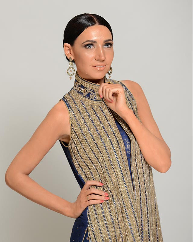 Woman wearing a sleeveless dress with a patterned design against a plain background