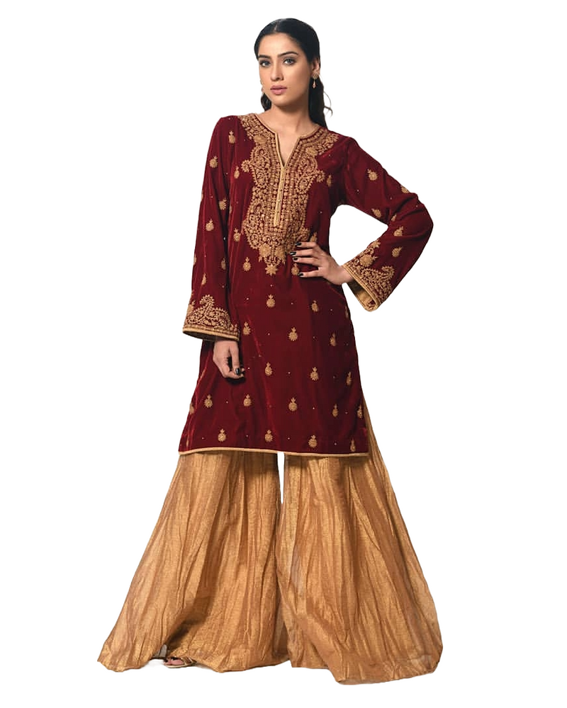 Woman wearing a traditional maroon and gold outfit on a white background