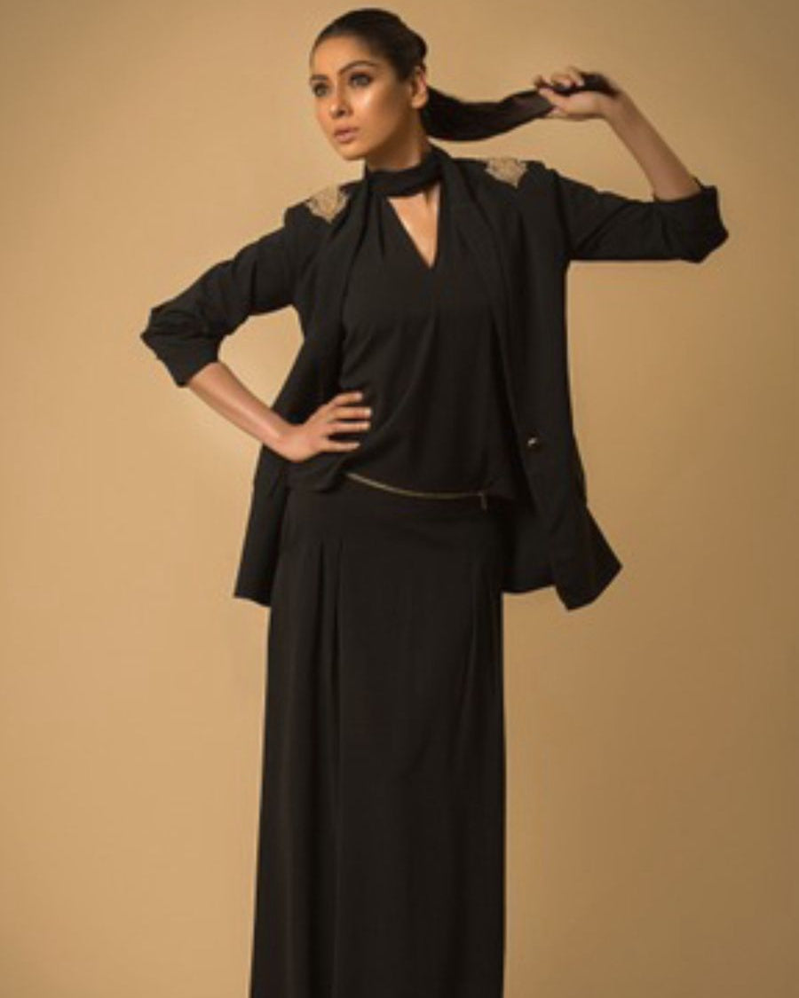 Woman in a black outfit posing against a beige background