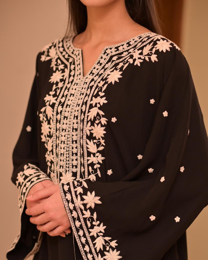 Black garment with white floral embroidery on a plain background