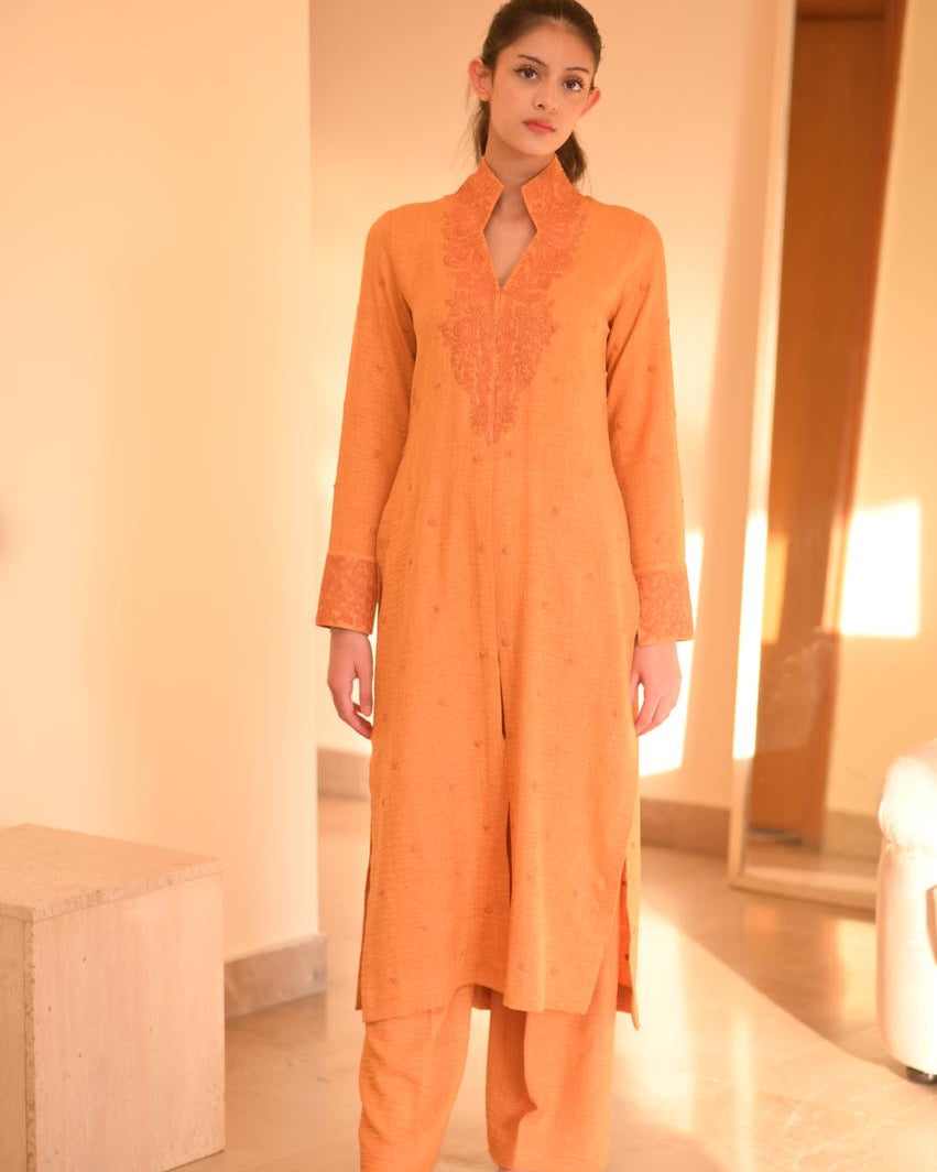 Woman wearing an orange traditional outfit in a well-lit room.